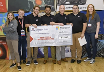 University students with presenter giving them a large award check