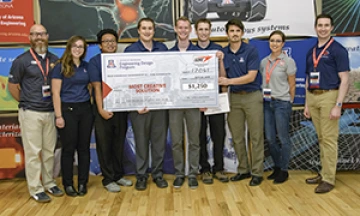 University students with presenter giving them a large award check