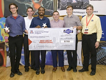 University students with presenter giving them a large award check