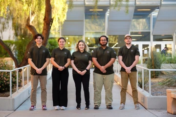 a group of five students poses outdoors