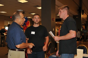 Talk between university staff and sponsors at an open house event Three men talking in a ballroom during an open house event