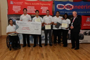 University students with presenter giving them a large award check