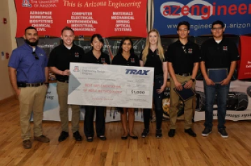 University students with presenter giving them a large award check