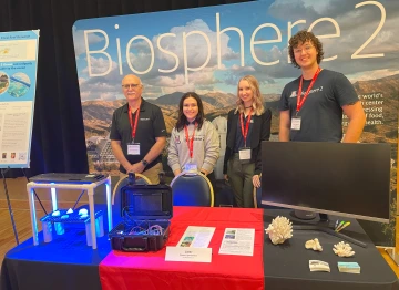 Four people stand at a conference display