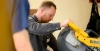 A man with red hair cuts a piece of metal with a large saw.