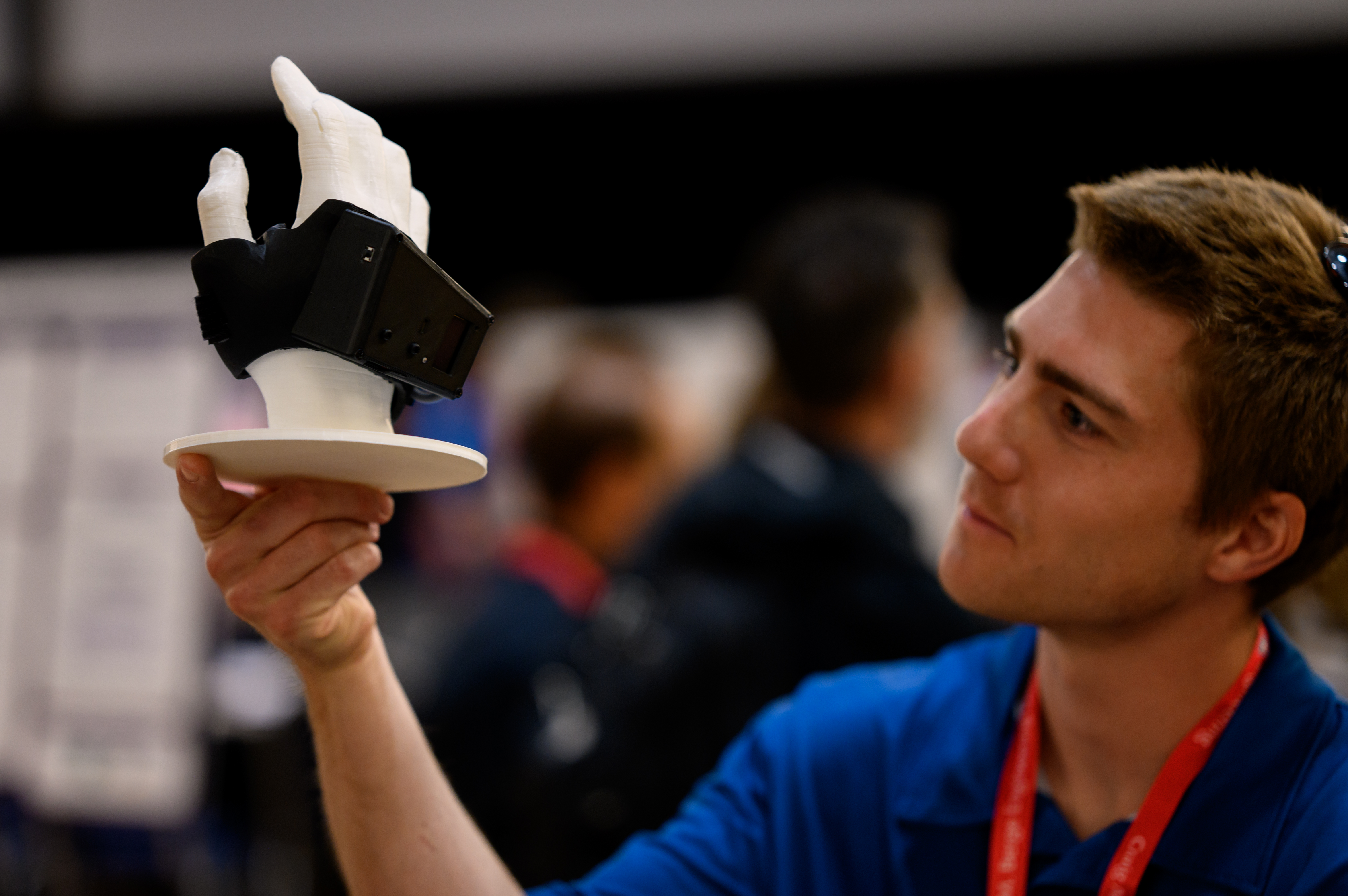 A judge inspects a brace attached to an artifical hand on a pedestal