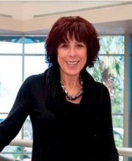 An image of Sharon ONeal in a black outfit standing in front of windows