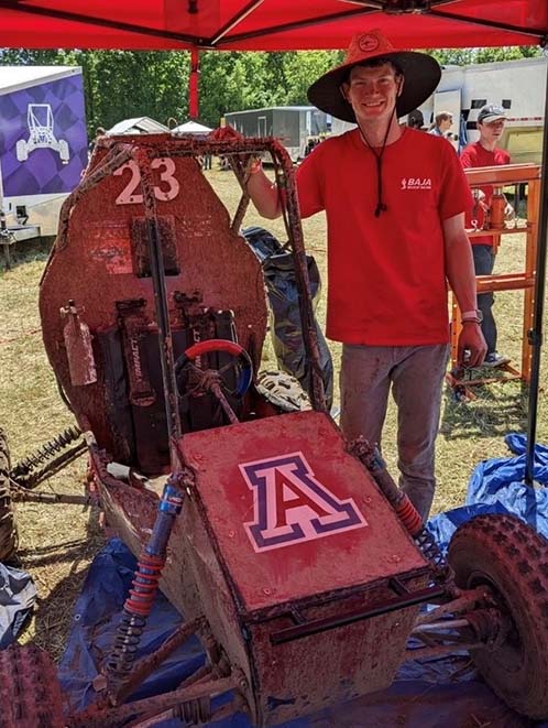 a student standing with a racecar