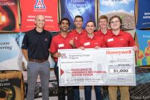 A group of five students and their sponsor holding a giant check.