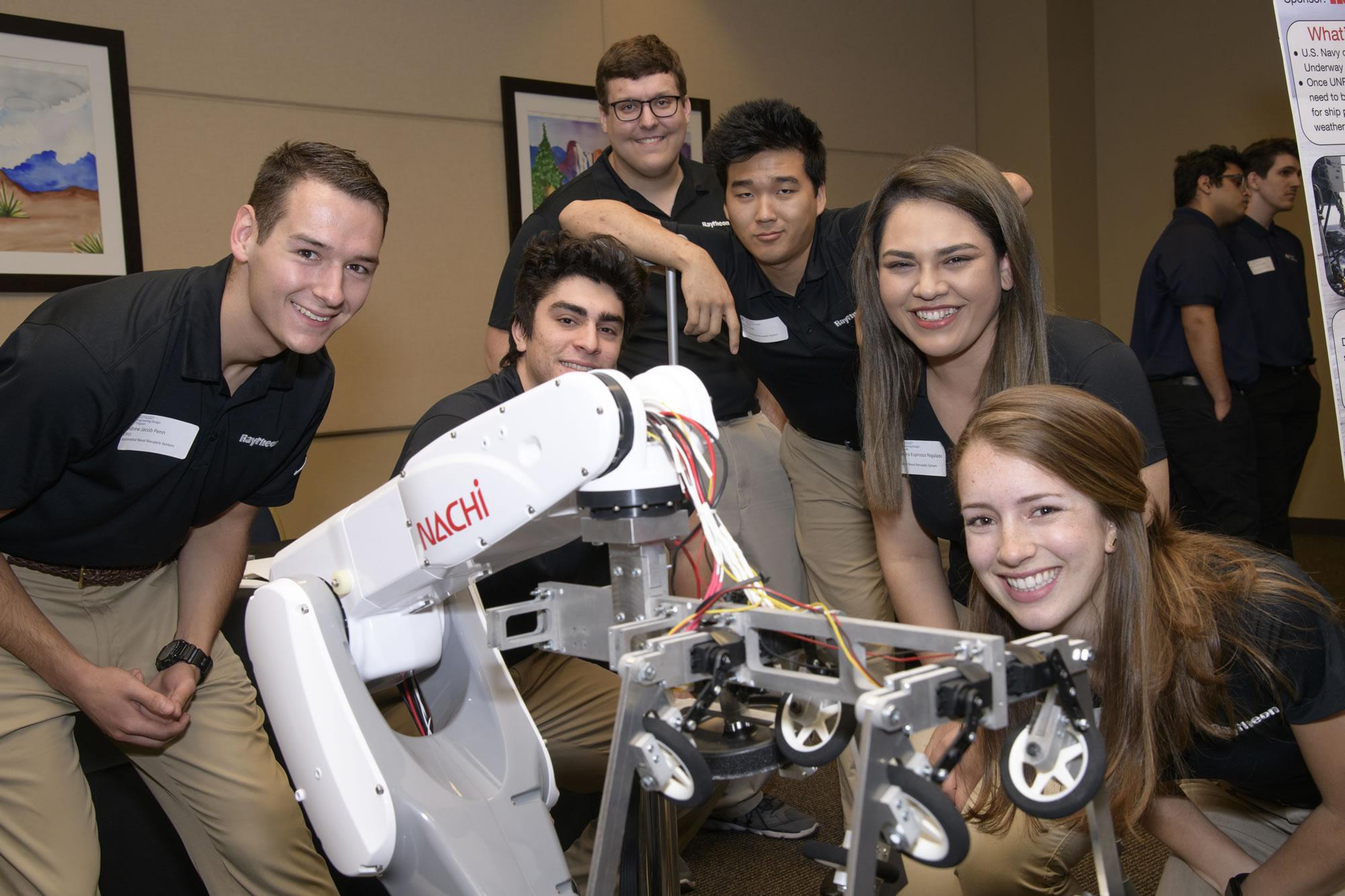 A senior design team stands with their robotics project