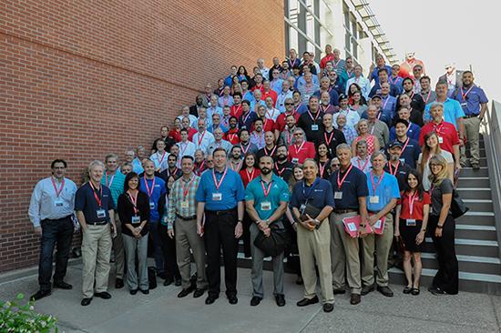 Large group of men and women standing on a staircase and all wearing red lanyards