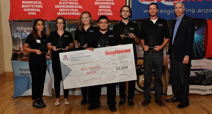 Sponsor presenting large award check and glass triangle-shaped awards to six university students