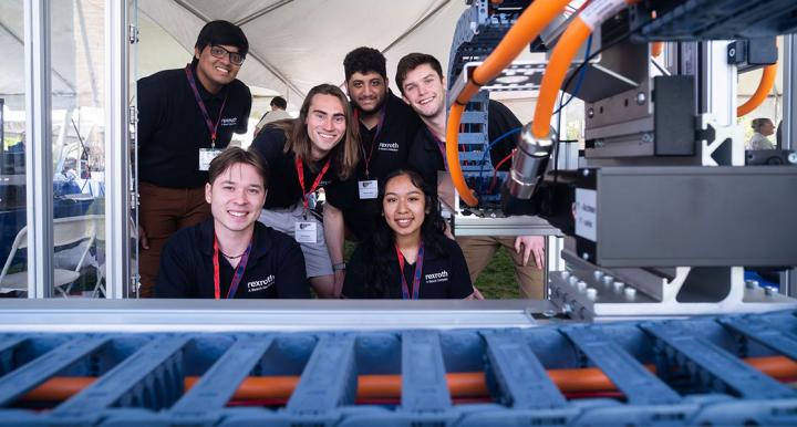 6 students pose with a manufacturing device
