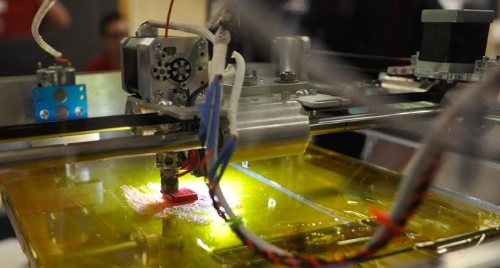 Close up image of a 3D printer making a red object