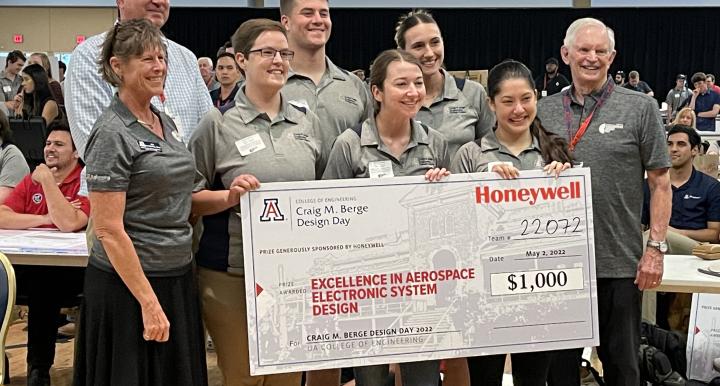 Eight people pose with a large prize check.