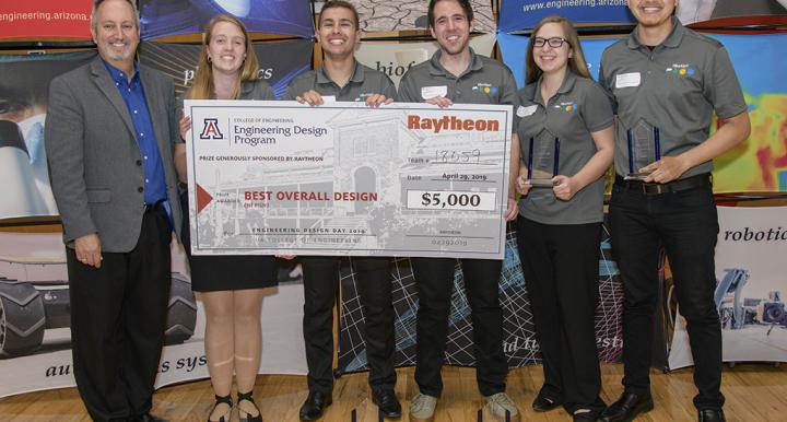 Man in suit with 5 students holding large award check