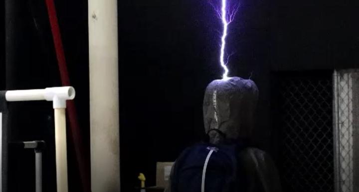 A mannequin in a dark room being struck by lightning