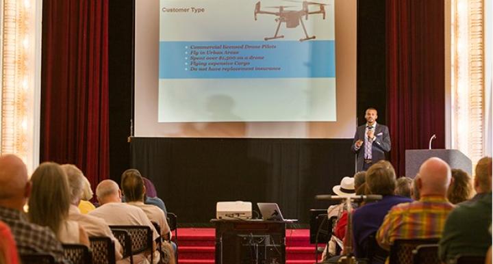 A group of people in an audience watching a presentation on drones